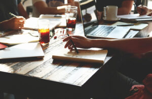 This is a Pixabay image showing peope meeting at a table with coffee notebooks and computers to go along with an article about medtech clinical trial design planning for startups.